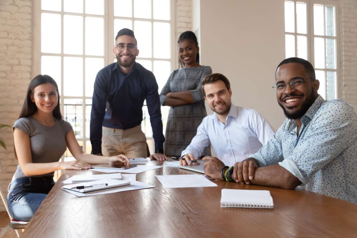 Portrait of happy diverse young businesspeople gather at boardroom table